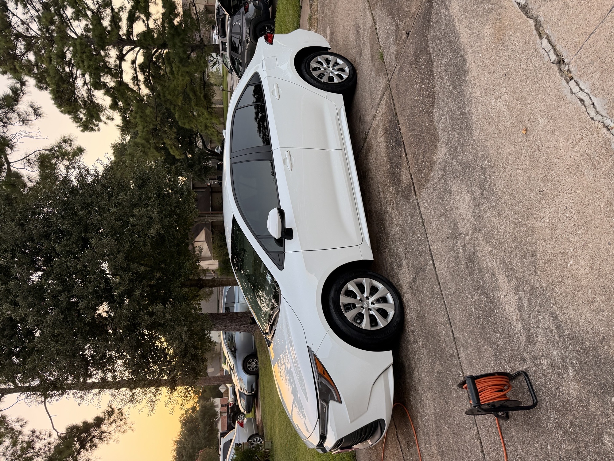 White Toyota Corolla shining in a driveway at sunset after a mobile wash